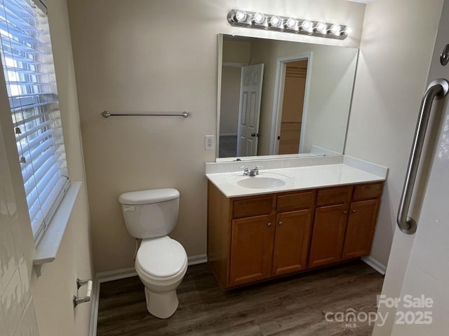 bathroom with wood finished floors, toilet, and vanity