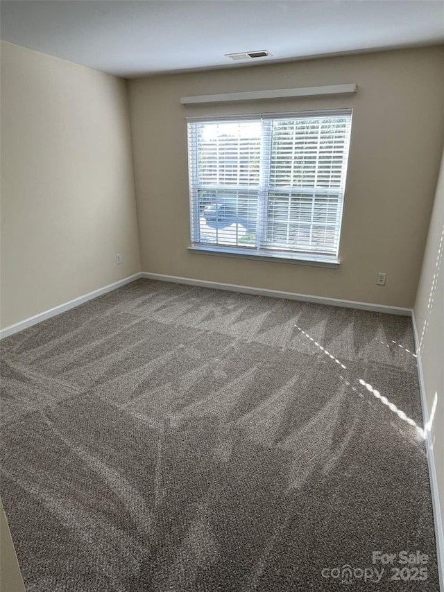 carpeted spare room featuring visible vents and baseboards