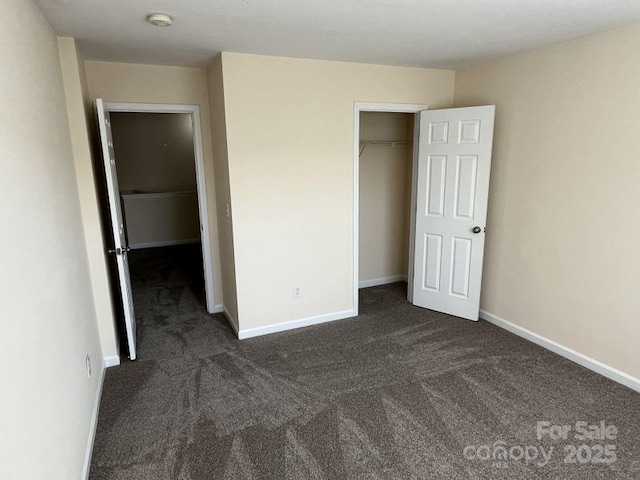 unfurnished bedroom featuring a closet, dark colored carpet, and baseboards