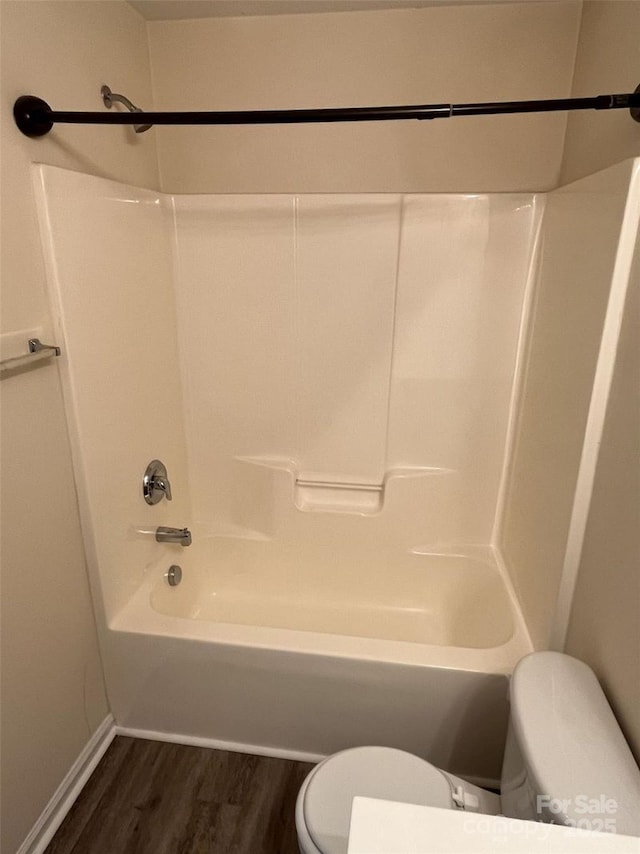 full bath with baseboards, wood finished floors, toilet, and shower / bathtub combination