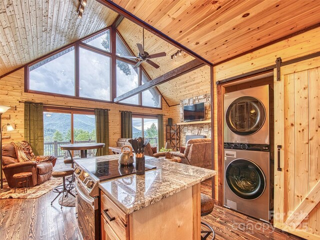 171 Jade Dr, Clyde, NC 28721 - kitchen featuring stacked washing machine and dryer, stainless steel electric range, wooden walls, open floor plan, and wood-type flooring