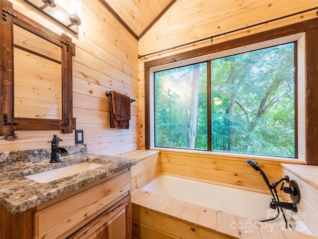171 Jade Dr, Clyde, NC 28721 - bathroom featuring plenty of natural light, wood walls, vaulted ceiling, vanity, and a bath