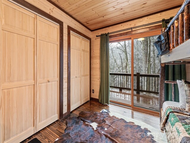 171 Jade Dr, Clyde, NC 28721 - bedroom with dark wood-style flooring, wooden walls, wooden ceiling, two closets, and access to outside