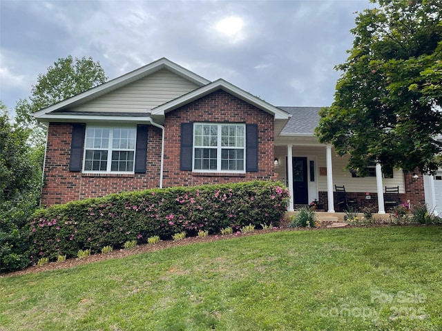 view of front of house with brick siding, a front lawn, and covered porch