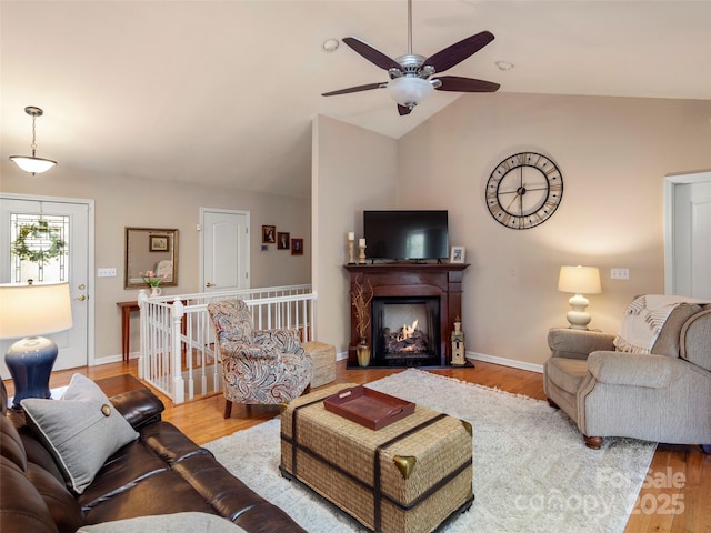 living room featuring vaulted ceiling, ceiling fan, baseboards, and wood finished floors