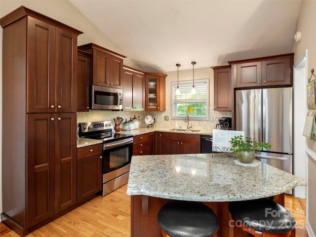 kitchen featuring backsplash, a kitchen breakfast bar, stainless steel appliances, and a sink