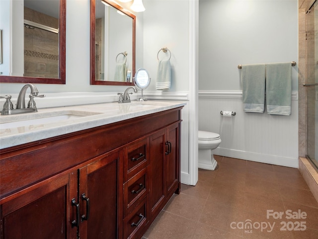 full bath with a wainscoted wall, a sink, double vanity, and a stall shower