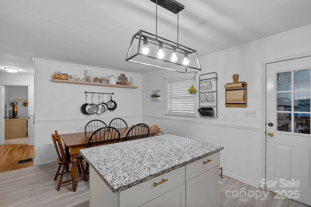 4314 Oak Forest Dr, Charlotte, NC 28215 - kitchen featuring a center island, light stone counters, visible vents, and light wood-style flooring