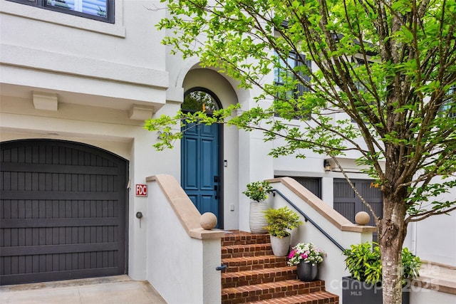 doorway to property featuring stucco siding and a garage