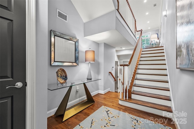 staircase featuring visible vents, vaulted ceiling, wood finished floors, and baseboards