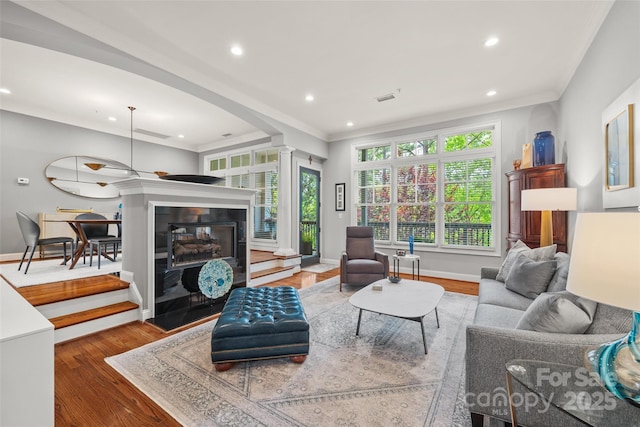 living room with recessed lighting, ornate columns, crown molding, baseboards, and wood finished floors