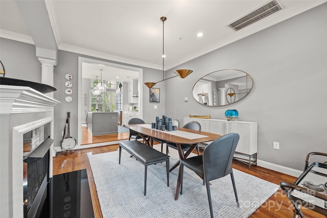 dining space featuring crown molding, visible vents, wood finished floors, and a fireplace