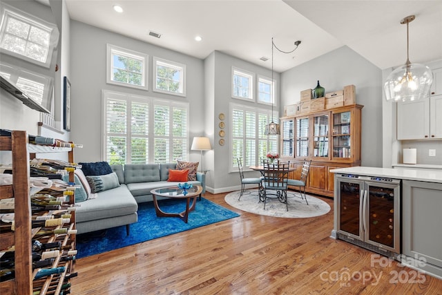 living area featuring visible vents, beverage cooler, a high ceiling, and light wood-style flooring