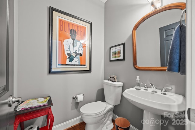 bathroom featuring toilet, wood finished floors, and baseboards