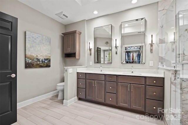 full bathroom with recessed lighting, a marble finish shower, a sink, and double vanity