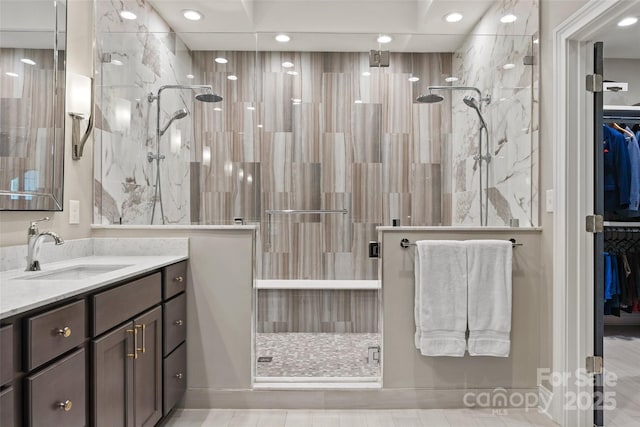 bathroom with a walk in closet, recessed lighting, a shower stall, and vanity