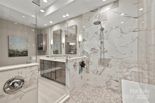 bathroom with recessed lighting, a marble finish shower, and vanity
