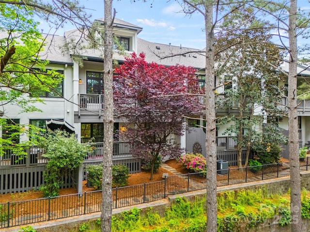 exterior space with a shingled roof, fence private yard, stucco siding, and a balcony