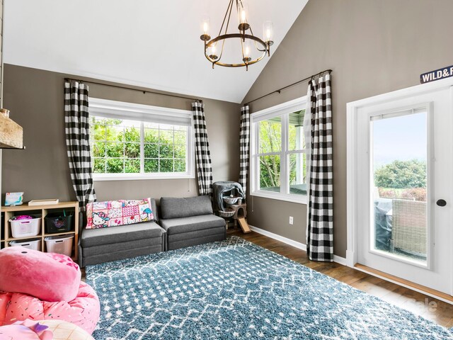 living area with baseboards, wood finished floors, a notable chandelier, and vaulted ceiling