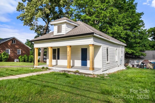 bungalow-style house featuring covered porch, a shingled roof, and a front yard
