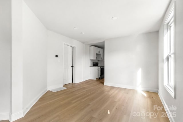 unfurnished living room with light wood-type flooring and baseboards