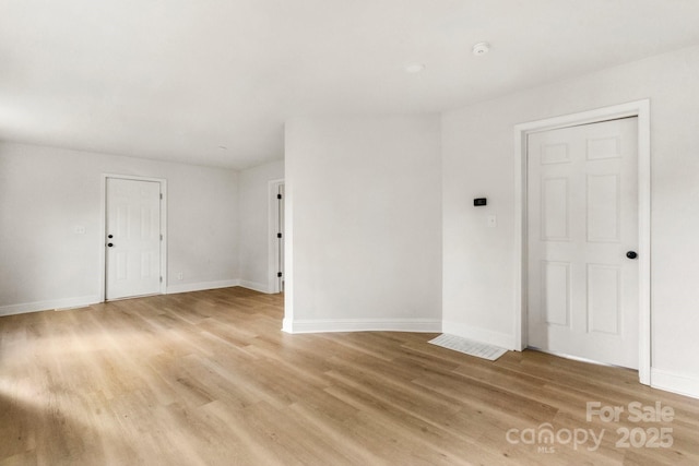 empty room with baseboards and light wood-type flooring