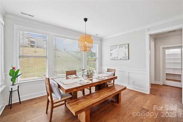 528 Rock Skip Way, Fort Mill, SC 29708 - dining room featuring light wood-type flooring, a chandelier, ornamental molding, healthy amount of natural light, and a wainscoted wall