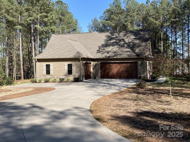 view of front of property with driveway, roof with shingles, and an attached garage