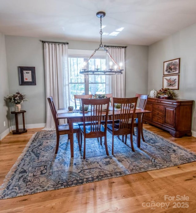dining room with a chandelier, wood finished floors, and baseboards