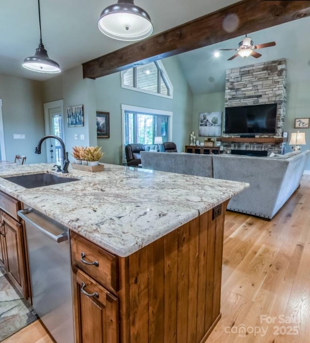 kitchen with a sink, a ceiling fan, stainless steel dishwasher, open floor plan, and light wood-style flooring