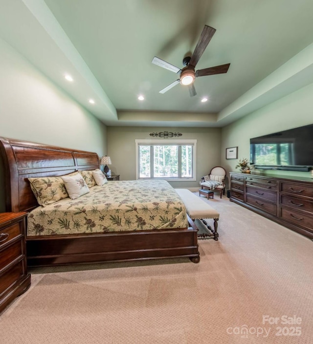 bedroom with a tray ceiling, light colored carpet, recessed lighting, and ceiling fan