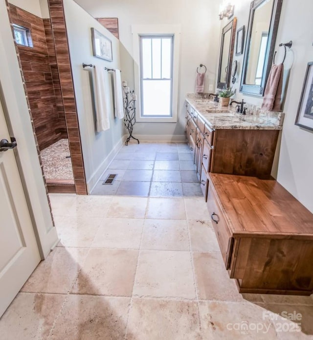 full bathroom with baseboards, double vanity, walk in shower, and tile patterned flooring