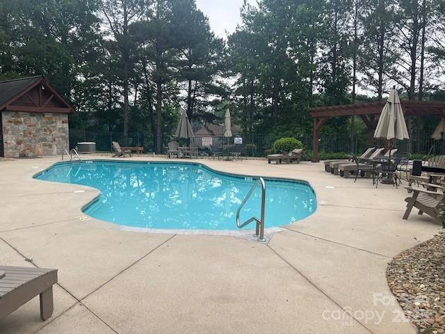 community pool featuring a patio area, a pergola, and view of scattered trees