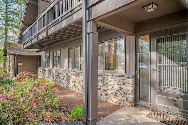 view of exterior entry featuring a balcony and stone siding