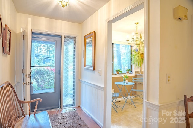 foyer entrance featuring a wainscoted wall, a wealth of natural light, wood finished floors, and a notable chandelier