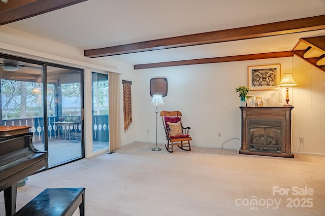 sitting room with carpet floors, beamed ceiling, a glass covered fireplace, and baseboards