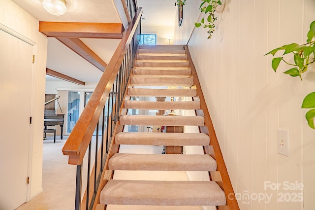 stairway with beamed ceiling and carpet flooring