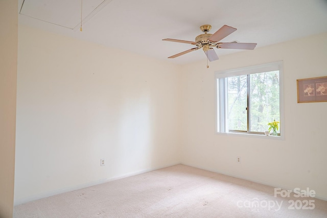 unfurnished room featuring baseboards, light colored carpet, ceiling fan, and attic access