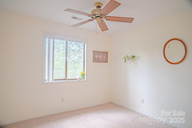 carpeted empty room featuring visible vents, a ceiling fan, and baseboards