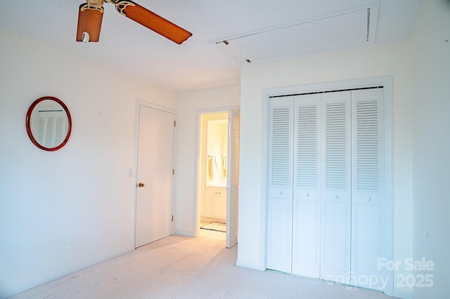 unfurnished bedroom featuring a closet, baseboards, attic access, ceiling fan, and light colored carpet