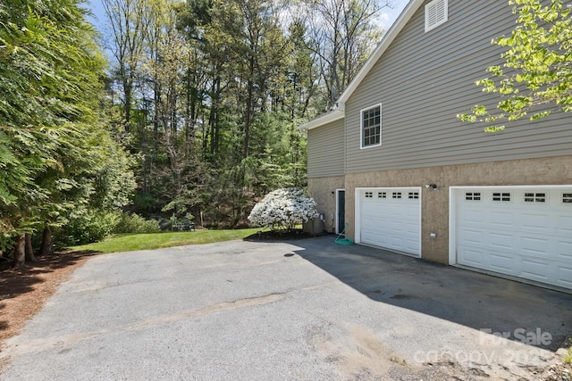 view of home's exterior with stucco siding, aphalt driveway, and a garage