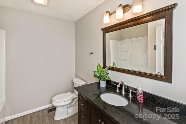 bathroom featuring wood finished floors, vanity, baseboards, toilet, and visible vents