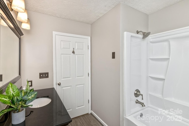full bath featuring bathtub / shower combination, vanity, wood finished floors, and a textured ceiling