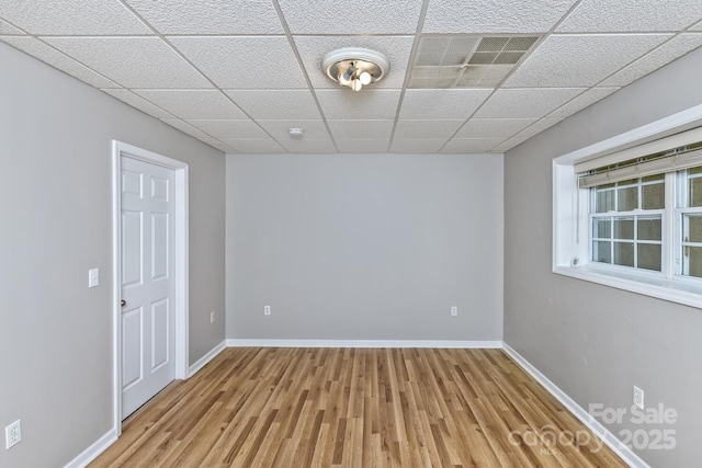 spare room featuring baseboards, wood finished floors, and a paneled ceiling