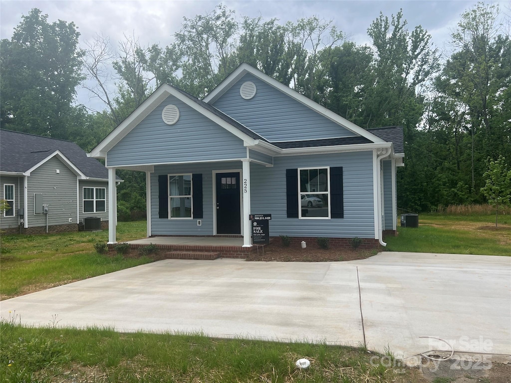bungalow featuring a front lawn, covered porch, and central air condition unit
