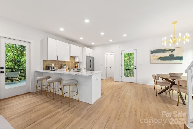 1847 Vinton St, Charlotte, NC 28216 - kitchen featuring a peninsula, stainless steel fridge, light wood-type flooring, a chandelier, and a breakfast bar area