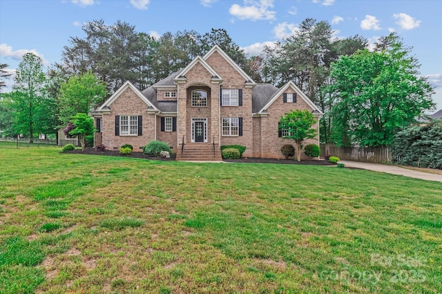 traditional-style house with brick siding, fence, and a front lawn