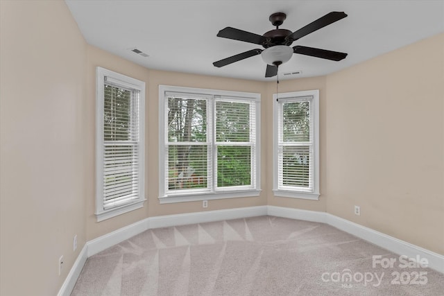 carpeted empty room featuring visible vents, a ceiling fan, and baseboards