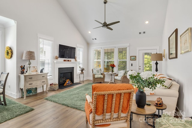 living area featuring visible vents, a glass covered fireplace, ceiling fan, high vaulted ceiling, and recessed lighting