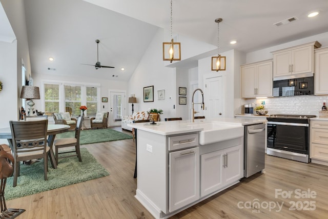 kitchen with light countertops, stainless steel appliances, high vaulted ceiling, and a sink